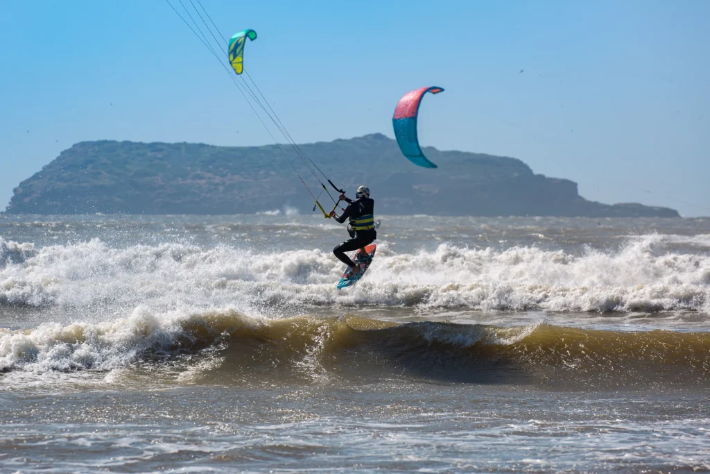 Kitesurfer riding waves in Essaouira, Morocco with scenic island in the background